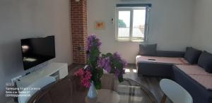 ein Wohnzimmer mit einem Sofa und einem Tisch mit lila Blumen in der Unterkunft KATARINA in Pakoštane