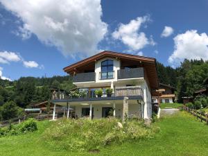 ein Haus mit einem Balkon auf einem Grasfeld in der Unterkunft Appartement Germann in Neukirchen am Großvenediger