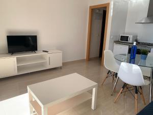 ein Wohnzimmer mit einem Tisch und einem TV in der Unterkunft Trebol One Apartments By Mc in Benidorm