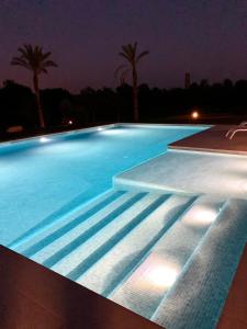 una gran piscina por la noche con palmeras en Bio Resort Mediterráneo, en Sant Martí Sarroca