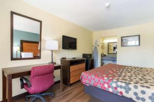 a hotel room with a bed and a desk and a chair at Econo Lodge Gallatin - Metro Nashville in Gallatin