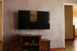 TV de pantalla plana colgada en la pared en Compleet vrijstaand woonhuis Paramaribo, en Paramaribo