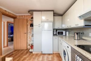 a kitchen with white cabinets and a white refrigerator at Zumaiako Txapitula - BasKey rentals in Zumaia