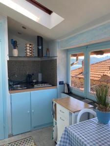 kuchnia z niebieskimi szafkami, stołem i oknem w obiekcie Apartment Italian Charm w mieście Ghiffa
