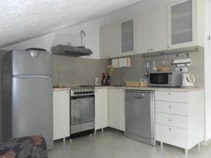 a kitchen with white cabinets and stainless steel appliances at Apartments David in Perast