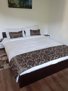 un grande letto con piumone marrone e bianco di Casa Moșoiu a Bran