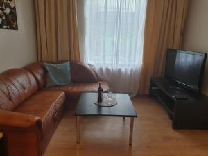 a living room with a brown leather couch and a table at blatoapartament in Sopot