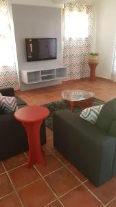 a living room with a couch and a tv at Hotel Casas do Sol in São Filipe