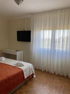 a bedroom with a bed and a large window at Casa do Tavares in Carvalhais