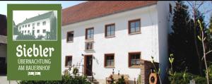 a large white building with a sign in front of it at Siebler Übernachtungen am Bauernhof in Wolnzach