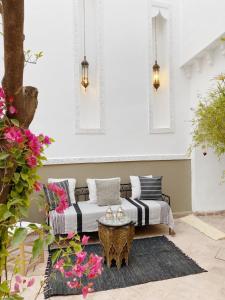 a patio with a couch and a table and flowers at Private house Riad Arlette exclusive in Marrakesh