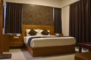 Schlafzimmer mit einem großen Bett und schwarzen Vorhängen in der Unterkunft Heritage Inn in Mysore