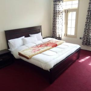 1 dormitorio con 1 cama grande con almohadas blancas y ventana en Hunza Regency Inn, en Hunza