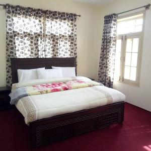 1 dormitorio con 1 cama y una ventana con cortinas en Hunza Regency Inn, en Hunza