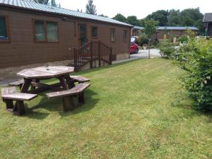 una mesa de picnic en un patio junto a una casa en Squirrel Lodge, en Clearwell