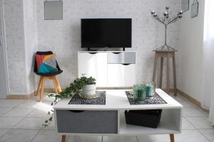 ein Wohnzimmer mit einem weißen Tisch und einem TV in der Unterkunft L'appartement d'Alexander in Troyes