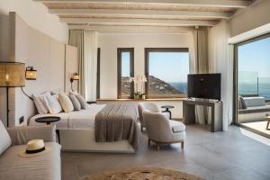 a bedroom with a bed and a tv and a couch at Amyth of Mykonos Super Paradise in Super Paradise Beach