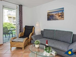 una sala de estar con un sofá, sillas y una mesa de cristal en Villa Maria Gabriele Whg 02, en Stubbenfelde