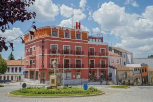 un edificio rosa con una fuente frente a él en Hospedaria Robalo, en Sabugal