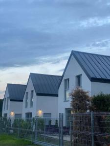 拜罗格拉Bosman Domki的两栋白色房屋,在栅栏后面有黑色屋顶