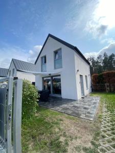 a white house with a fence in a yard at Bosman Domki in Białogóra