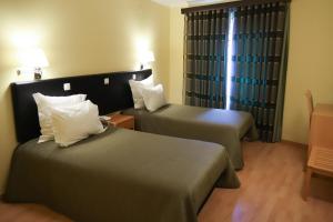um quarto de hotel com duas camas e uma janela em Hospedaria Robalo no Sabugal