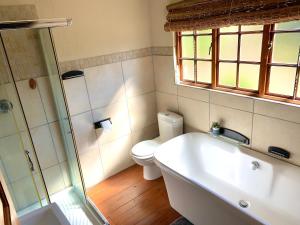 a bathroom with a tub and a toilet and a window at Hope Haven Cottage in Nelspruit