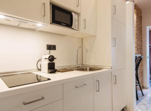 cocina con armarios blancos, fregadero y microondas en Suites Triana Sevilla Apartments en Sevilla