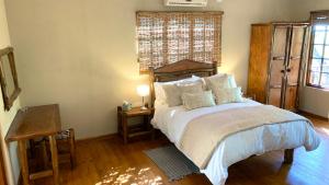 a bedroom with a bed and a table and a window at Hope Haven Cottage in Nelspruit