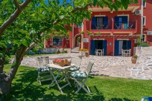 una mesa y sillas bajo un árbol frente a una casa en Aloe Studios, Waterfront Accommodation, en Karavádhos