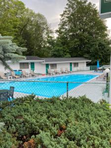a swimming pool with chairs and a building at Brookside Motel & Cabins in Lake George