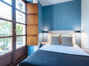 Dormitorio azul con cama y ventana en Suites Triana Sevilla Apartments, en Sevilla