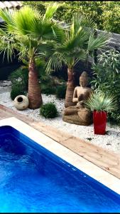 un jardín con una persona que medita y palmeras y una piscina en Villa carioca appartement bâbord, en Gujan-Mestras