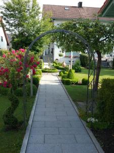 una passerella con arco in un giardino fiorito di Haus Pollak a Waldkirchen