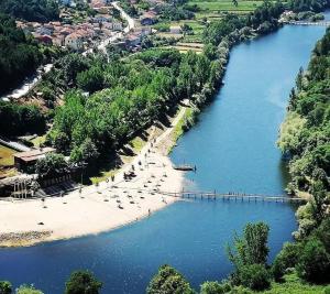 a bridge over a river with people on a beach at CASA do MONDEGO COIMBRA-17km in Penacova