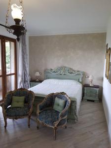 a bedroom with a bed and two chairs at Nel giardino di Dafne in Stresa