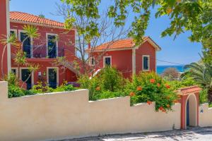 a red house with a fence and flowers at Aloe Studios, Waterfront Accommodation in Karavadhos