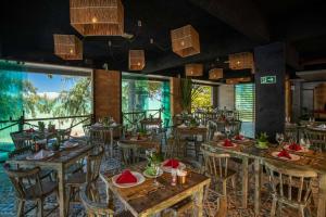 a restaurant with wooden tables and chairs and large windows at CHOUPANA SUÍTES in Japaratinga