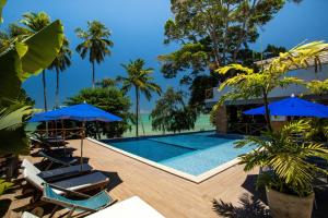 a pool at a resort with blue umbrellas at CHOUPANA SUÍTES in Japaratinga