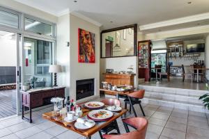a living room with a table and a fireplace at Blaauw Village Guest House in Bloubergstrand