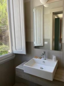 a bathroom with a sink and a mirror and a window at Guerrini Hotel in Castiglioncello