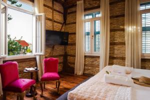 a bedroom with pink chairs and a bed and a tv at Libretto Suites in Lefkada