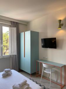a room with a desk and a cabinet with a tv at Guerrini Hotel in Castiglioncello