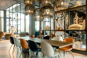 une salle à manger avec une table, des chaises et des lustres dans l'établissement Motel One Hamburg-Fleetinsel, à Hambourg
