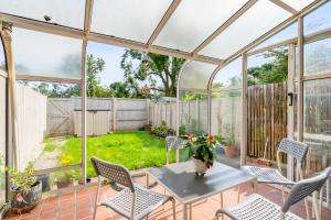 a conservatory with a table and chairs on a patio at NIKSA Serviced Accommodation - 3 bedroom house in Welwyn Garden City