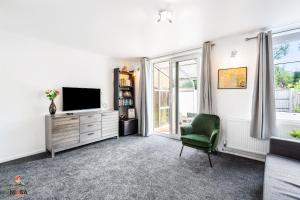 uma sala de estar com uma televisão e uma cadeira verde em NIKSA Serviced Accommodation - 3 bedroom house em Welwyn Garden City