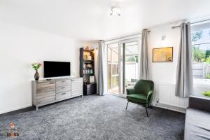 a living room with a television and a green chair at NIKSA Serviced Accommodation - 3 bedroom house in Welwyn Garden City