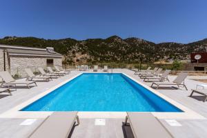 a pool with chaise lounge chairs and a resort at Omalos Village in Omalós