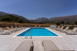 a pool with chaise lounge chairs and a swimming pool at Omalos Village in Omalós