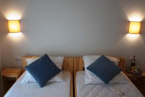 two beds in a room with two blue pillows at Laguna Kompleks Wypoczynkowo Rekreacyjny in Mrzeżyno